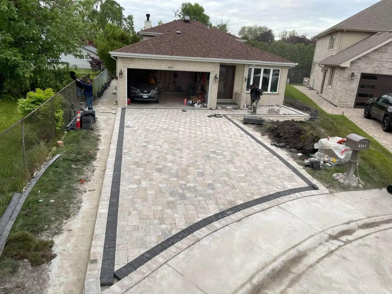 Finished paver driveway with charcoal border in front of a brick ranch home