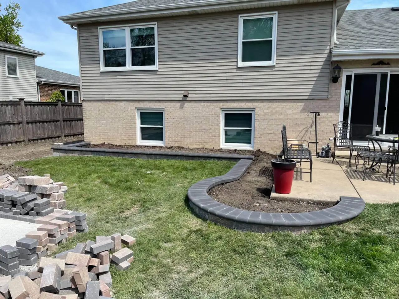 Charcoal paver seat wall border curving around a backyard patio