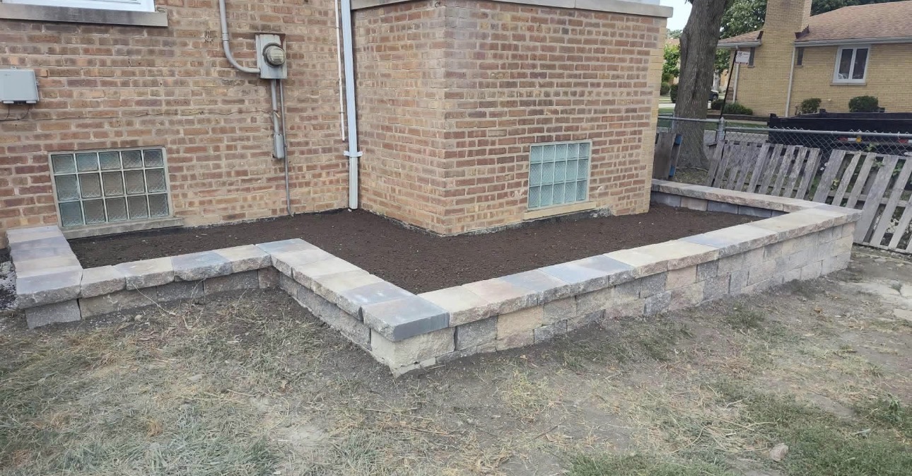 Finished tiered stone retaining wall bed filled with rich dark soil