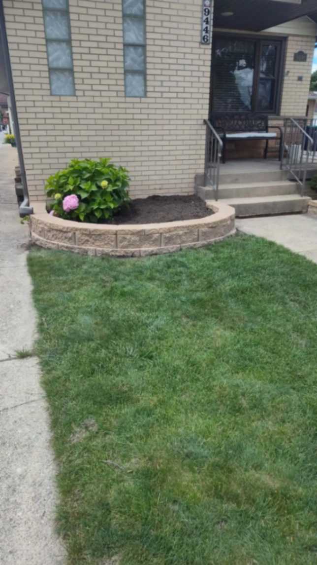 Curved block planter bed with hydrangea beside a brick home entry